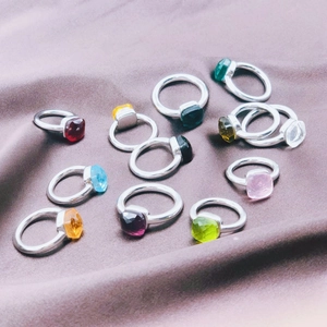 Flat lay of multiple stainless steel rings with colorful square zircon gemstones