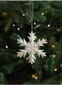 Detail of white glitter snowflake ornament with gold dust hanging on a Christmas tree