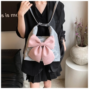 Detail view of silver velvet shoulder bag with a large pink bow in a stylish setup