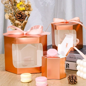 Macro shot of rose gold hexagonal gift boxes with pink satin ribbons and clear windows