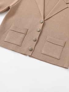Detail view of beige knit cardigan featuring a classic lapel collar and four buttons