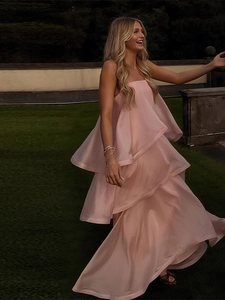 Détail d'une robe longue rose à volants étagés et fines bretelles sur gazon