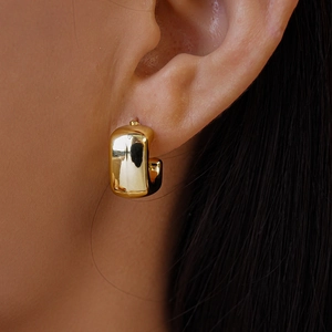 Close-up of a chunky gold U-shaped earring with a high-polished mirror finish