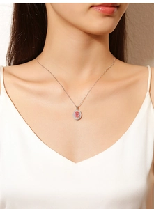 Close-up of pink oval gemstone pendant necklace with diamond halo on silver chain