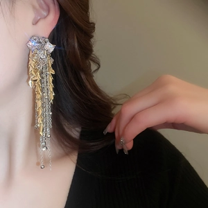 Close-up of long tassel earrings with sparkling rhinestones and gold leaf pendant details