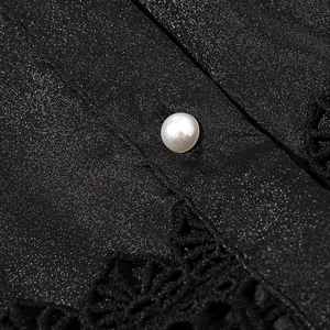 Detail of elegant black shimmering fabric with pearl button and lace embroidery