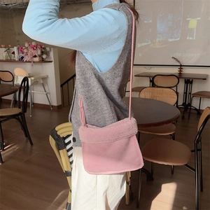 Sac bandoulière en daim rose avec bordure en peluche porté par un mannequin en café