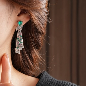 Close-up of vintage emerald teardrop earrings with colorful tassel fringe on model