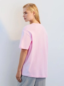 Πίσω όψη από ένα κομψό ροζ βαμβακερό t-shirt με χαλαρή εφαρμογή και στρογγυλή λαιμόκοψη