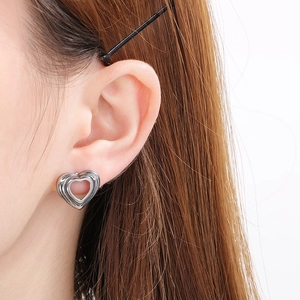 Close-up of minimalist hollow heart-shaped silver earrings worn on a model's ear