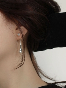 Detailed view of sterling silver drop earrings with white pearls on a female model
