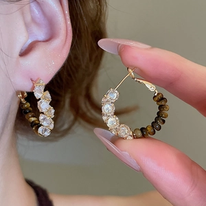 Detail view of 18k gold plated hoop earrings featuring tiger eye beads and cubic zirconia