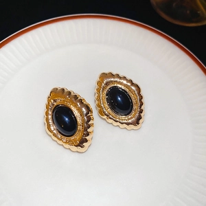 Macro detail of French vintage oval earrings with black stone and gold wavy metal base