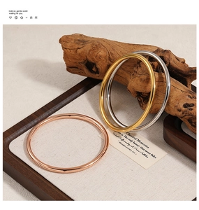 Close-up of minimalist 4mm solid metal bangles in gold, silver, and rose gold finishes