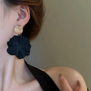 Details von großen schwarzen Spiralblumen-Ohrhängern am Modell mit goldener Hammerschlag-Optik