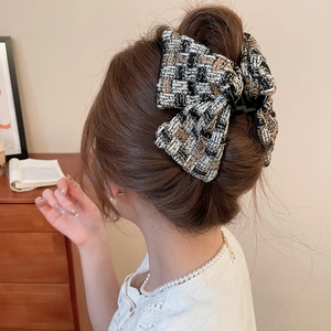 Détail d'une pince à cheveux en tweed avec nœud portée sur un chignon élégant et chic