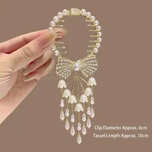 Détail d'une pince à cheveux dorée avec glands muguet et un nœud en cristal brillant