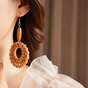 Détail de boucles d'oreilles bohèmes en rotin rond avec perles en bois sur un mannequin