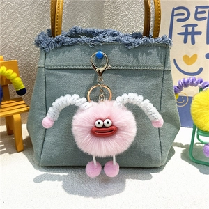 Pink plush monster keychain with red lips and metal clip shown as a backpack charm