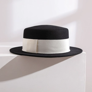 Elegant black wool felt boater hat with a wide white grosgrain ribbon on white stairs