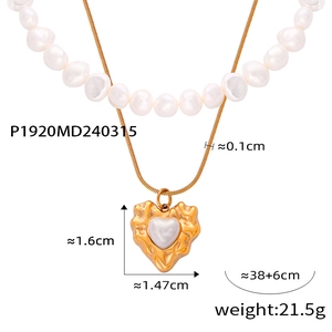 Detail of gold heart pendant with hammered texture and freshwater pearl on layered chain