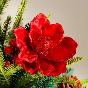 Red artificial Christmas flower with gold glitter edges and festive pine branches
