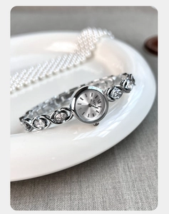 Vue macro d'une montre bracelet GEDI argentée avec zircons blancs sur fond de perles