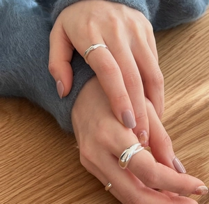 Three minimalist S925 sterling silver rings styled on a hand against a cozy sweater