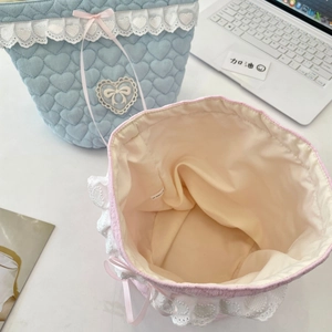 Detail of quilted fabric storage baskets with heart pattern, lace trim and bow ribbons