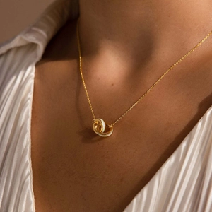Detailed view of intertwined gold and opal ring pendants on a titanium steel necklace