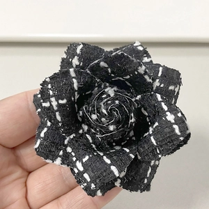 Detailed view of handmade black and white houndstooth tweed camellia flower brooch
