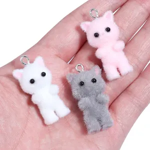 Three miniature flocked resin cat pendants in pink, white, and gray with silver metal rings