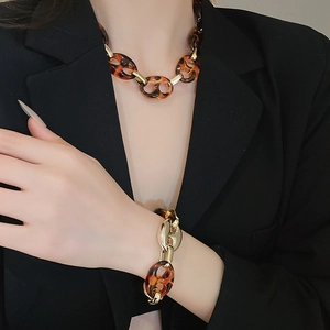 Dettaglio del set collana e bracciale in resina ambra e metallo dorato su modella