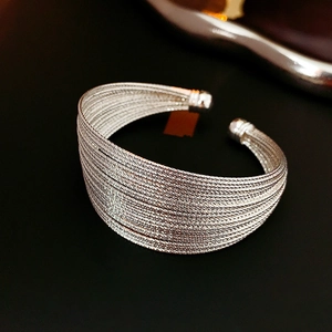 Macro shot of silver multi-layered woven open cuff bracelet with metallic luster