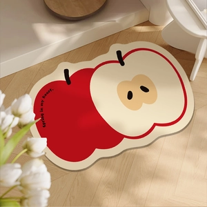 Absorbent apple-shaped bathroom floor mat with cute red and cream fruit design on wood floor
