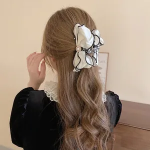 Elegant oversized beige fabric bow hair claw with pearls and black piping for long hair