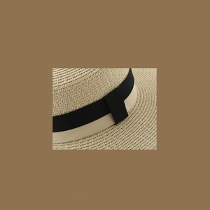 Close-up of natural woven straw hat featuring a black and yellow striped ribbon band