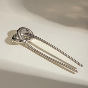 Macro shot of silver U-shaped hair pin with a polished twisted knot metal design