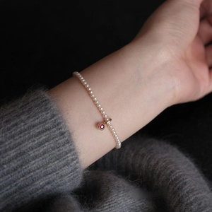 Elegant white pearl bracelet with a gold red zircon pendant charm on a model's wrist