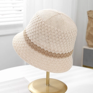 Detailed knit texture of beige summer bucket hat with brown stripes on a gold stand