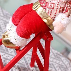 Weihnachtsmann-Puppe aus rotem Samt auf einer roten Leiter für Weihnachtsdekoration