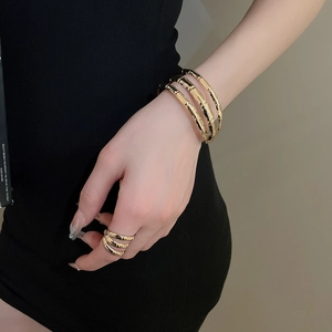 Detailed view of layered gold bamboo-style bracelet and ring set worn on model