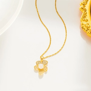 Detail of 18k gold flower pendant necklace with central pearl and sparkling crystals