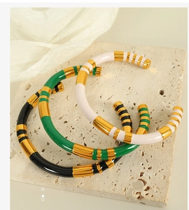 Detailed macro view of stacked striped enamel bangles on a textured stone display