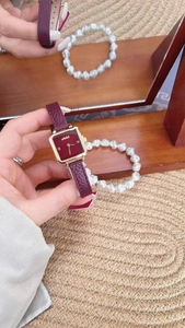 Close-up of a women's vintage square watch with a red dial and gold case on a red leather strap