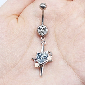 Macro shot of silver belly ring with blue heart stone, clear gem and small pearls