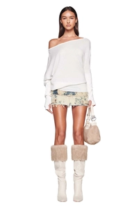 Close-up of white off-shoulder knit sweater with elongated sleeves and soft texture