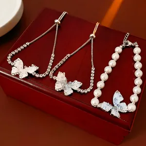Bracelets papillon élégants avec zircone et perles présentés sur un coffret bois