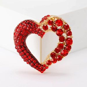 Detailed view of heart-shaped brooch with red rhinestones on a golden base