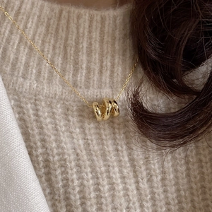 Close-up of gold corrugated triple-ring pendant on an elegant 925 silver chain necklace